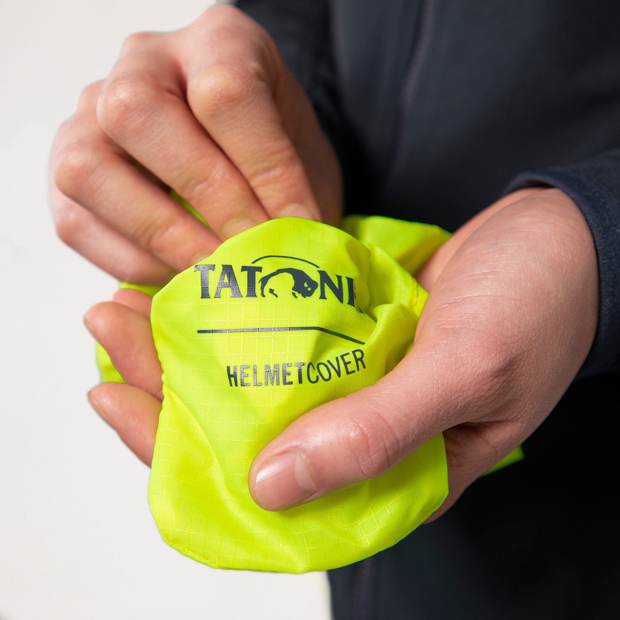 Tatonka Helmet Cover safety yellow gelb Regenhüllen - Detailansicht Finger, Hand, Person, Baby, Reinigen, Tatonka Helmet Cover safety yellow gelb Regenhüllen - Detailansicht